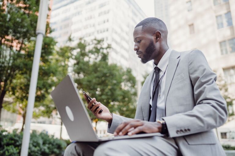 Businessman suivant ses actions commerciales sur un CRM accessible sur ordinateur et téléphone mobile